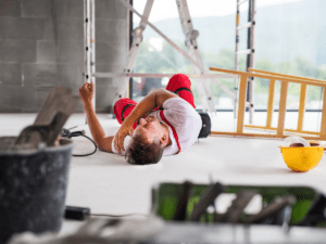 A construction worker on the ground in pain at a construction site.